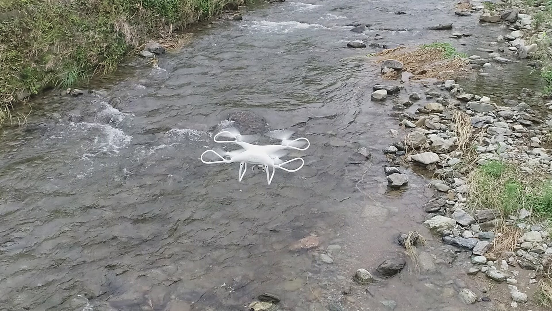 河辺の近くでドローン測量をするシーン